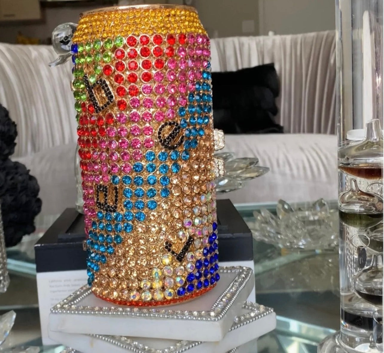 A sparkling, rhinestone-encrusted clutch in the shape of a soda can, featuring vibrant multicolored gems, a sleek metallic finish, and a detachable chain strap for versatile wear